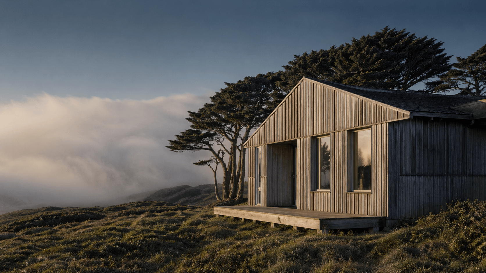 Timber residence on a grassy bluff above the Pacific with Pacific fog rolling in